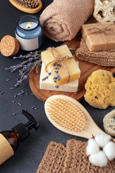Bath and body flatlay with soap bars, a candle, lavender and a wooden brush